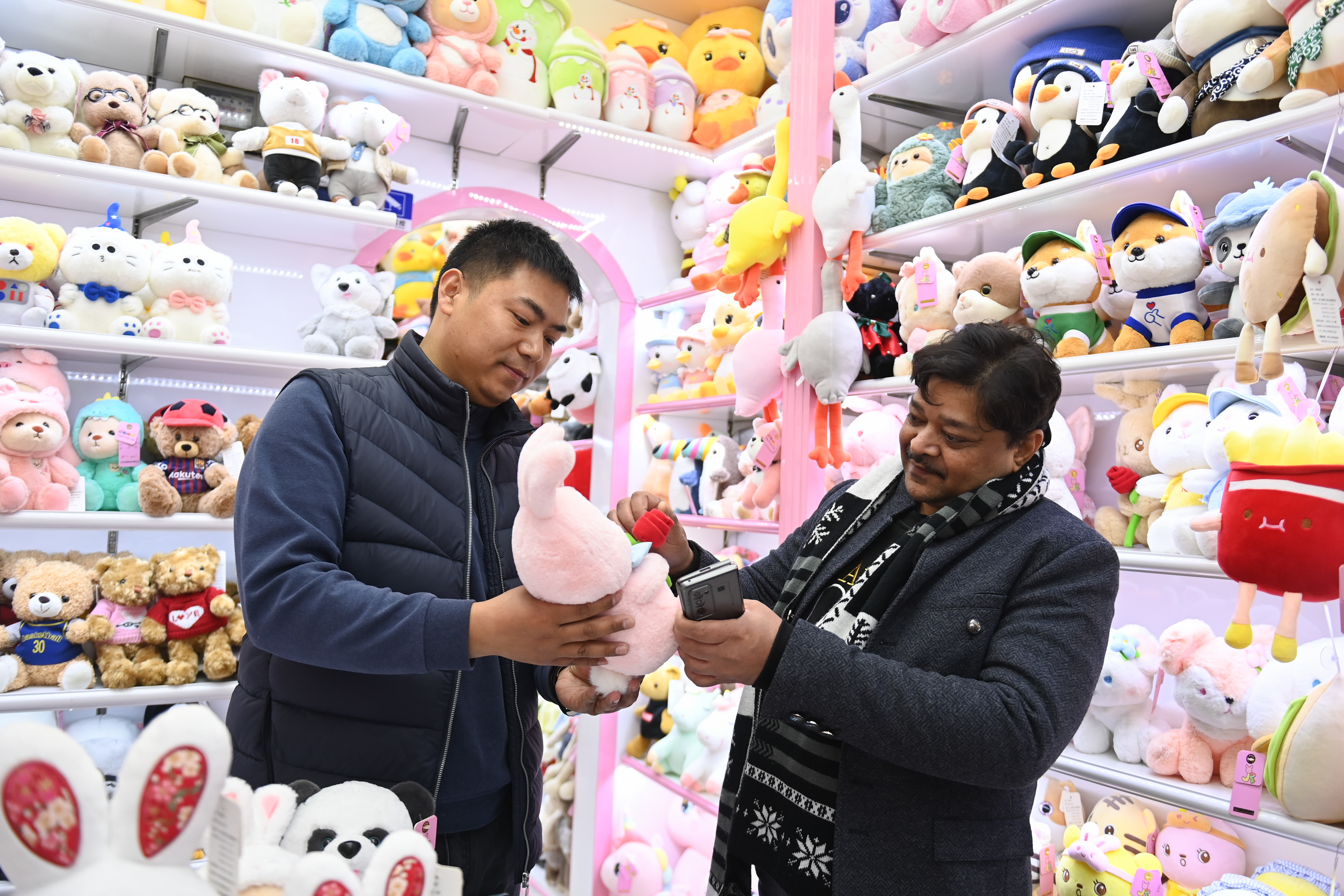 2023年2月2日，來自印度的客商（右）在義烏國際商貿(mào)城的一家玩具店鋪內(nèi)選購。